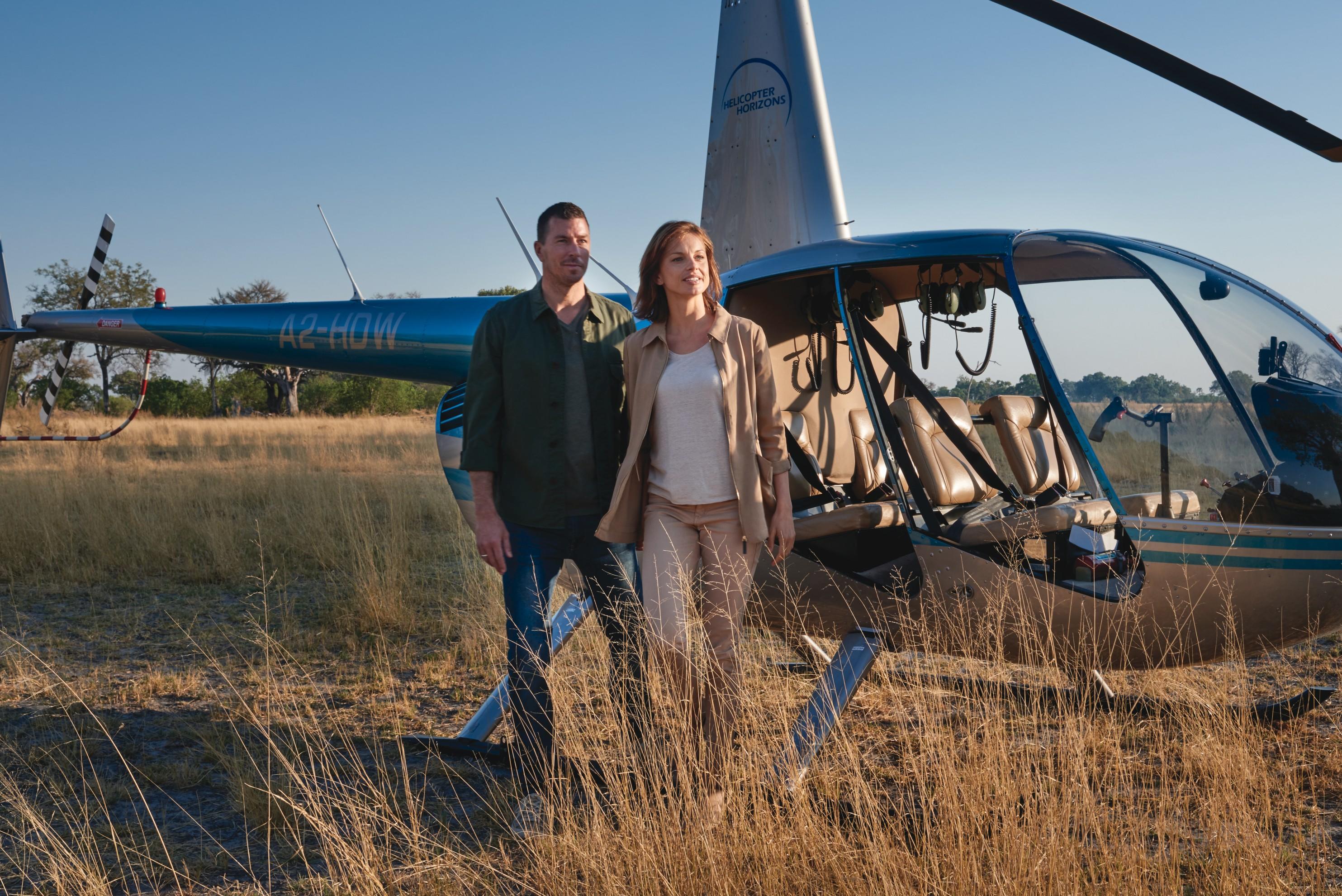 couple next to grounded helicopter arriving at Belmond Eagle Island Lodge