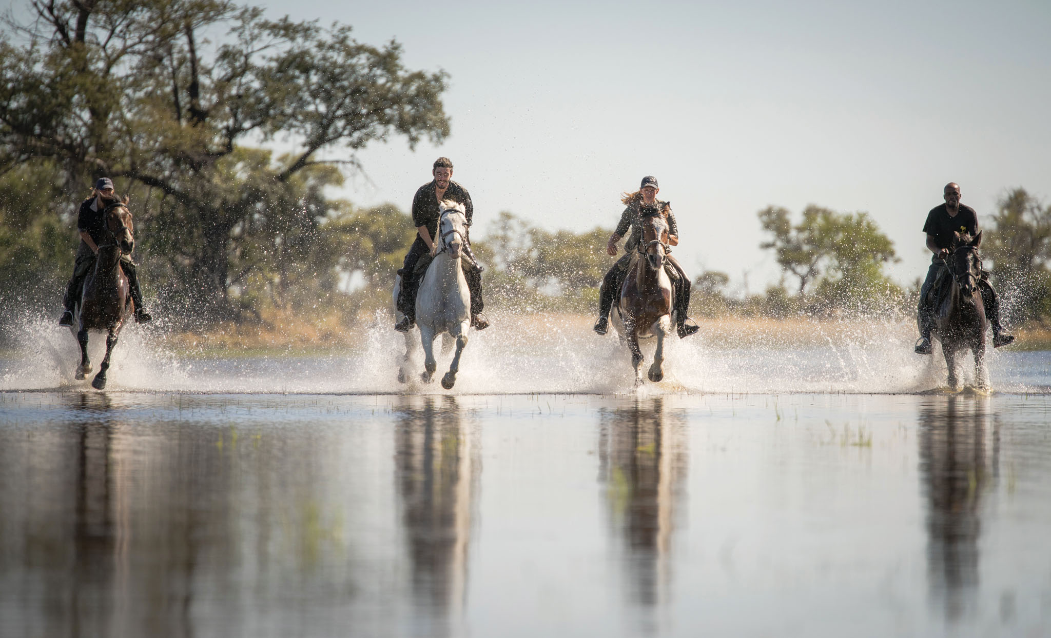 guests on horseback in the waters of the Okavango delta on a horseback safari by Belmond Eagle Island Lodge
