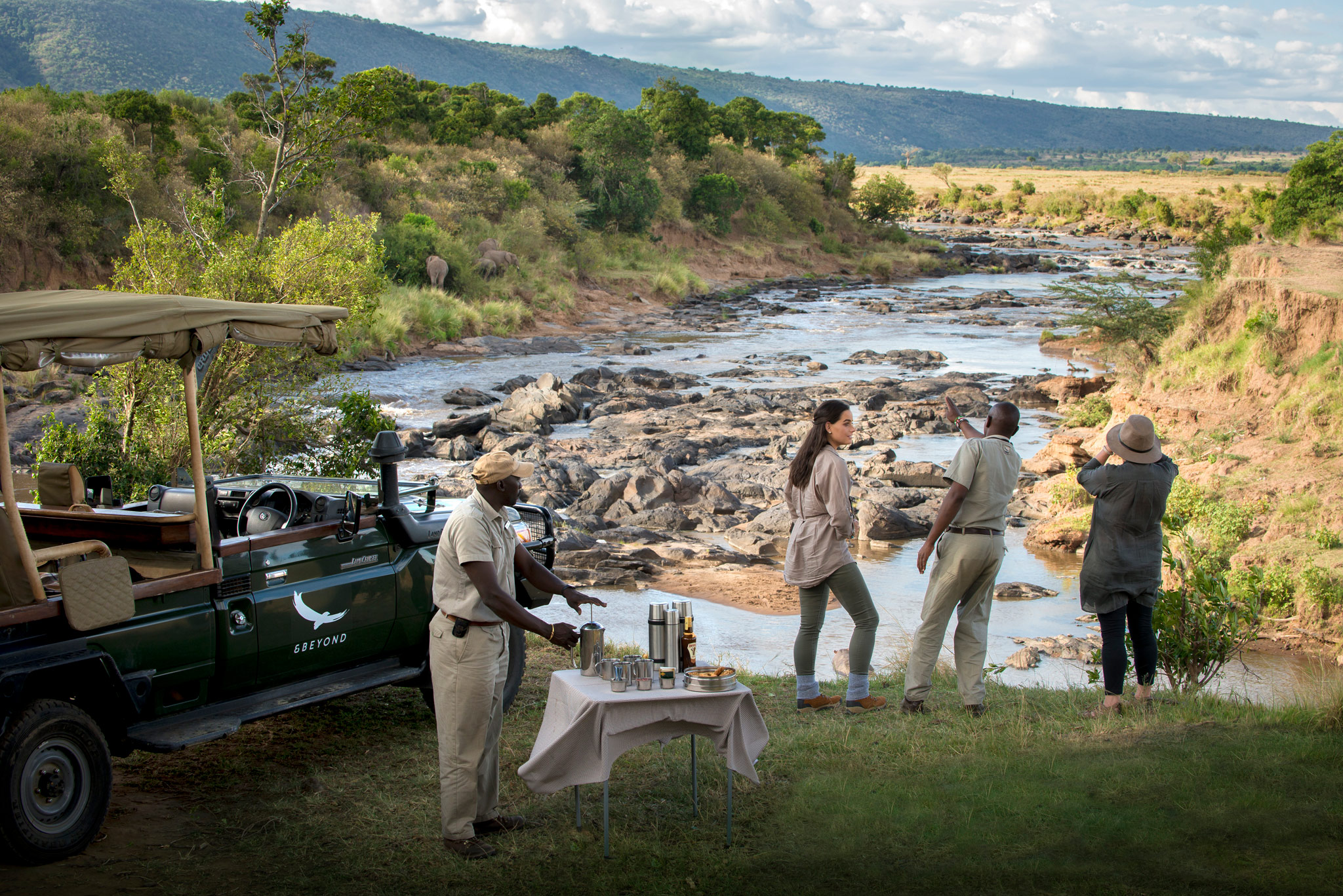 sundowners with guest and guide by river near andbeyond Bateleur camp Kenya Masai Mara