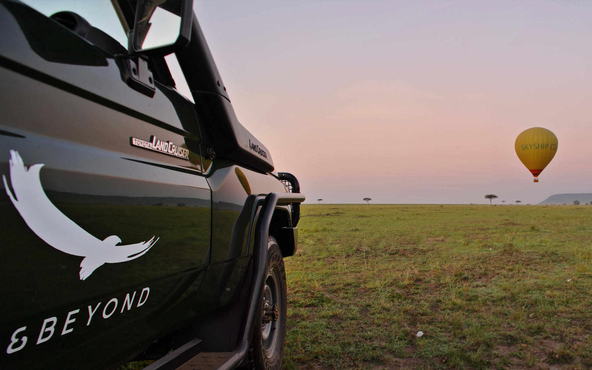 vehicle on plains with balloon in sky at andbeyond Bateleur camp Kenya Masai Mara