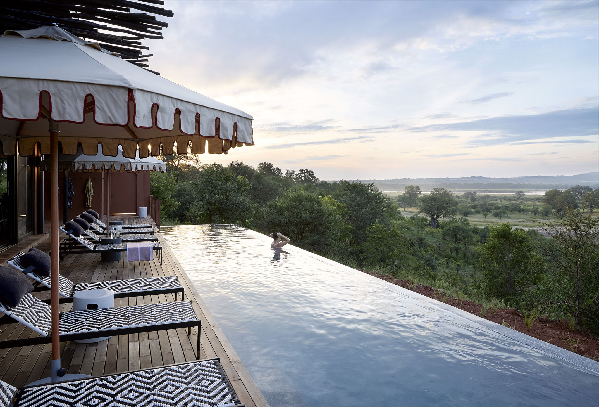 lady guest in pool on deck by main lodge of  Chichele Presidential Lodge Zambia