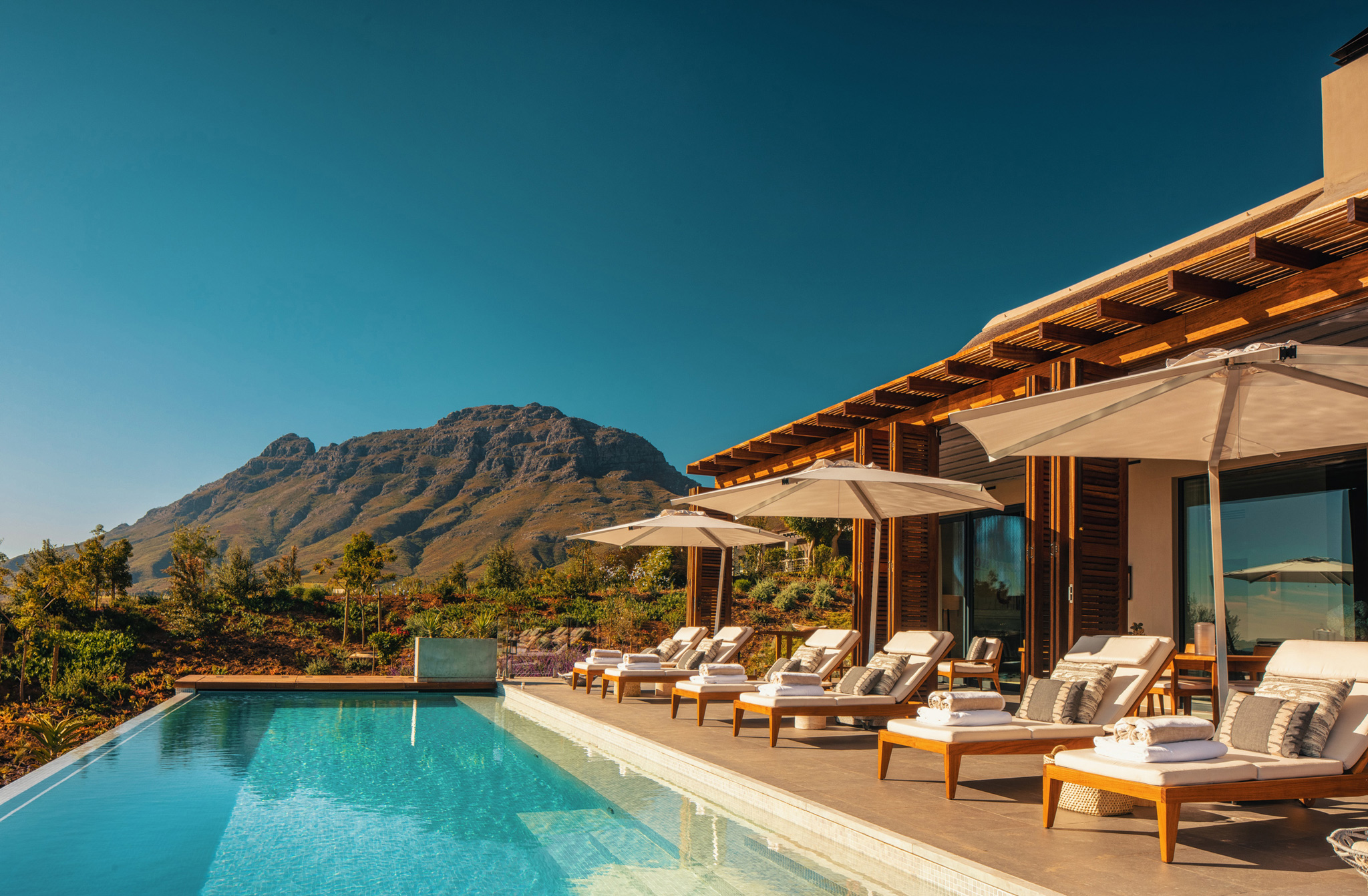 main villa pool area with loungers and umbrellas at Delaire Graff luxury Wine estate in Franshoek