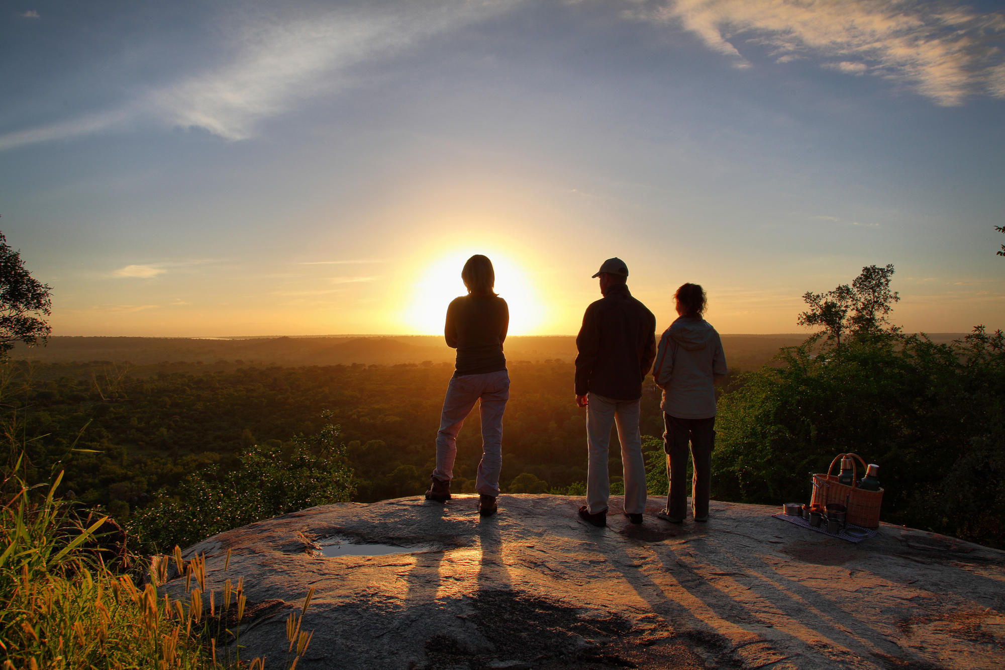 guests with guide on rocky outcrop looking at sunrise over malamala game lodge