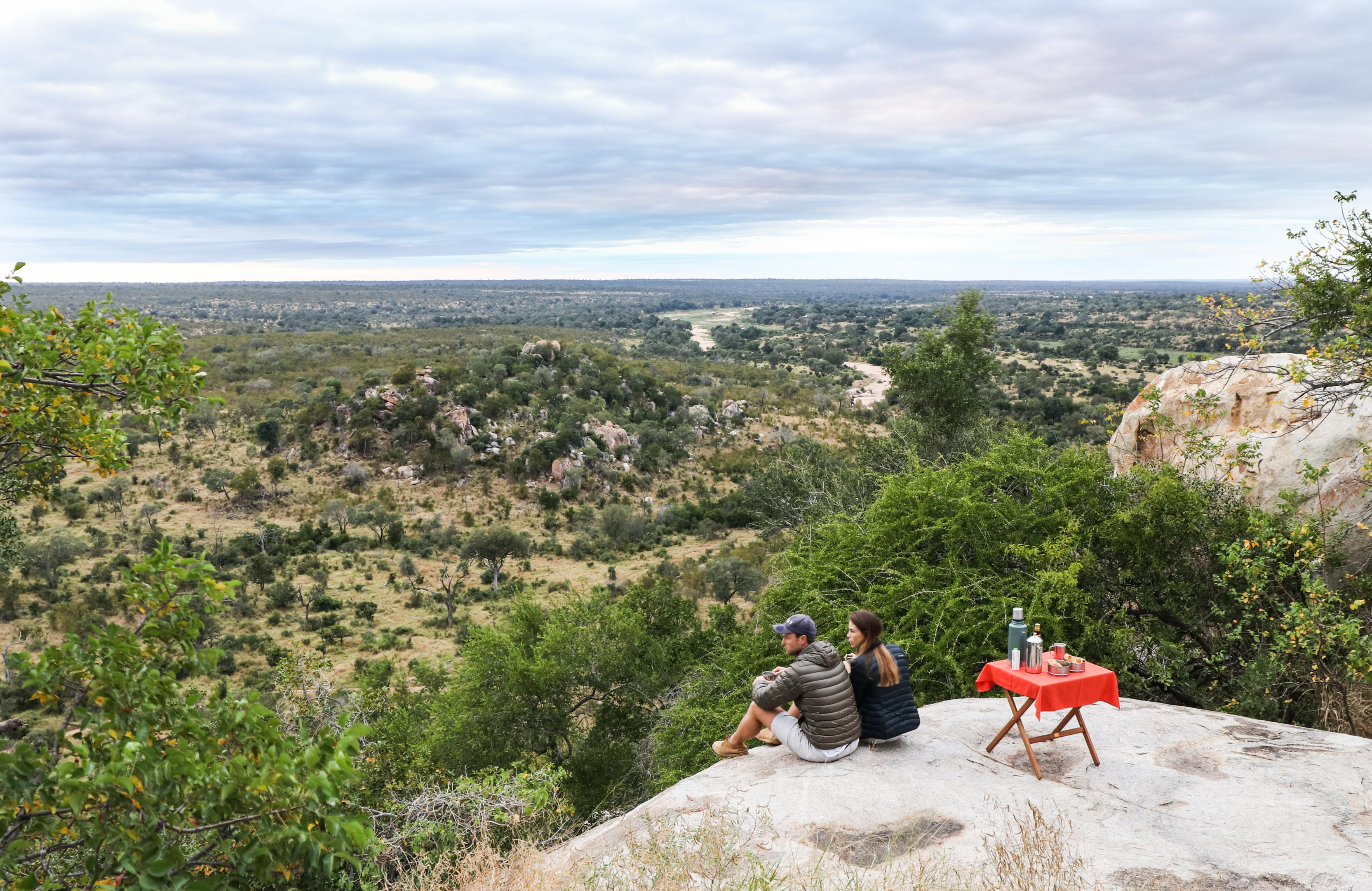 couple sitting on a rocky outcrop having sundowners at malamala game reserve