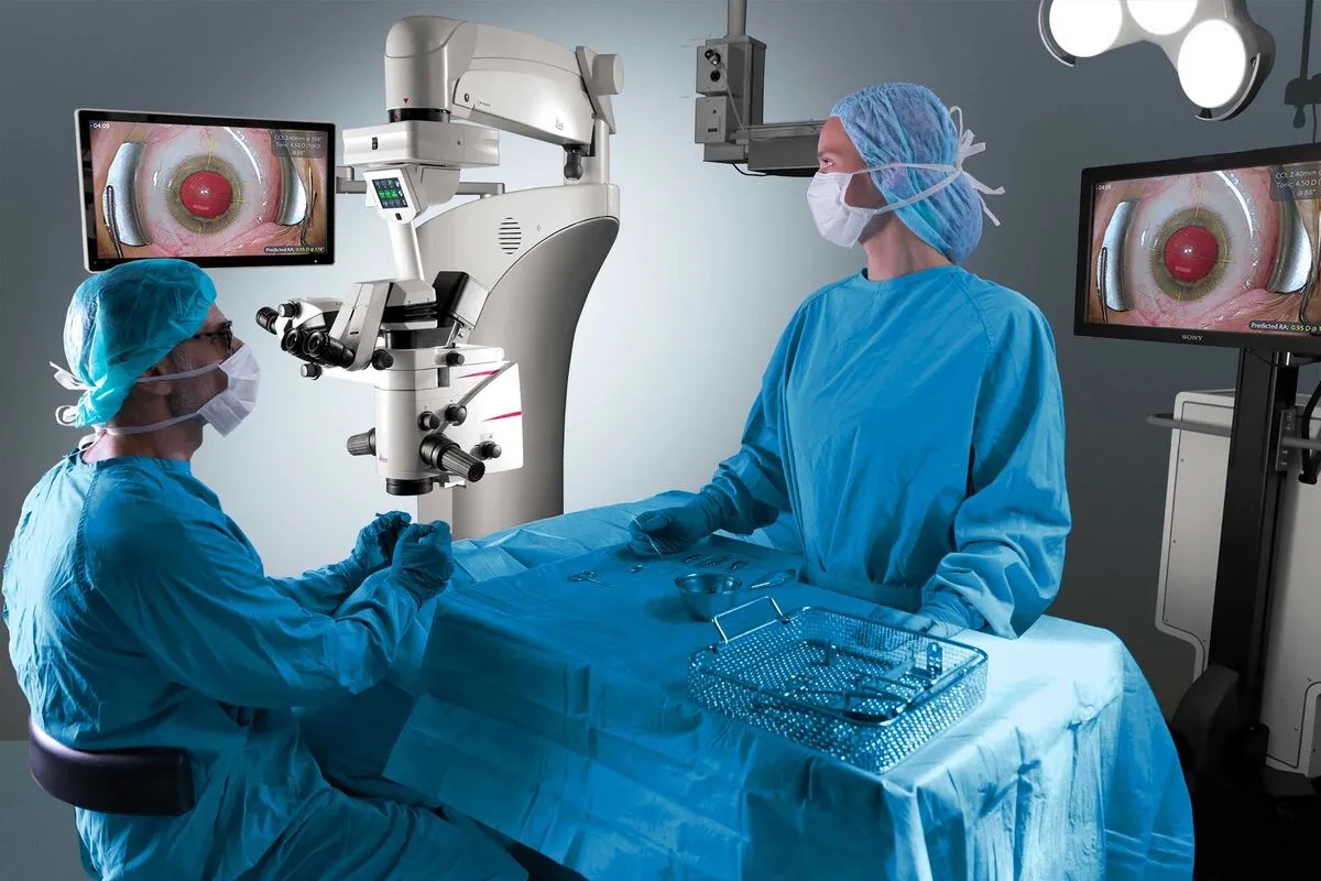 two surgeons performing eye surgery on patient with advanced microscopes