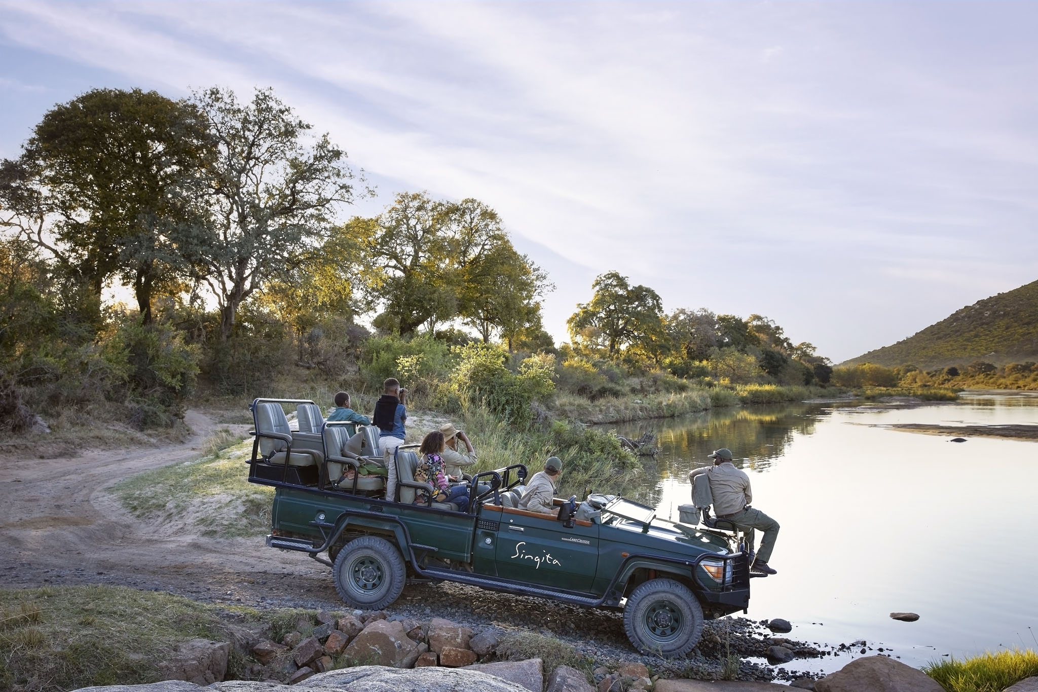 guests in safari vehicle about to cross river on a game drive at singita