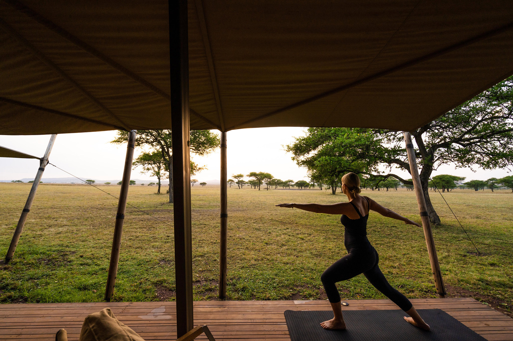 guest doing yoga in morning outside suite of Singita Sabora Tented Camp Serengeti 
