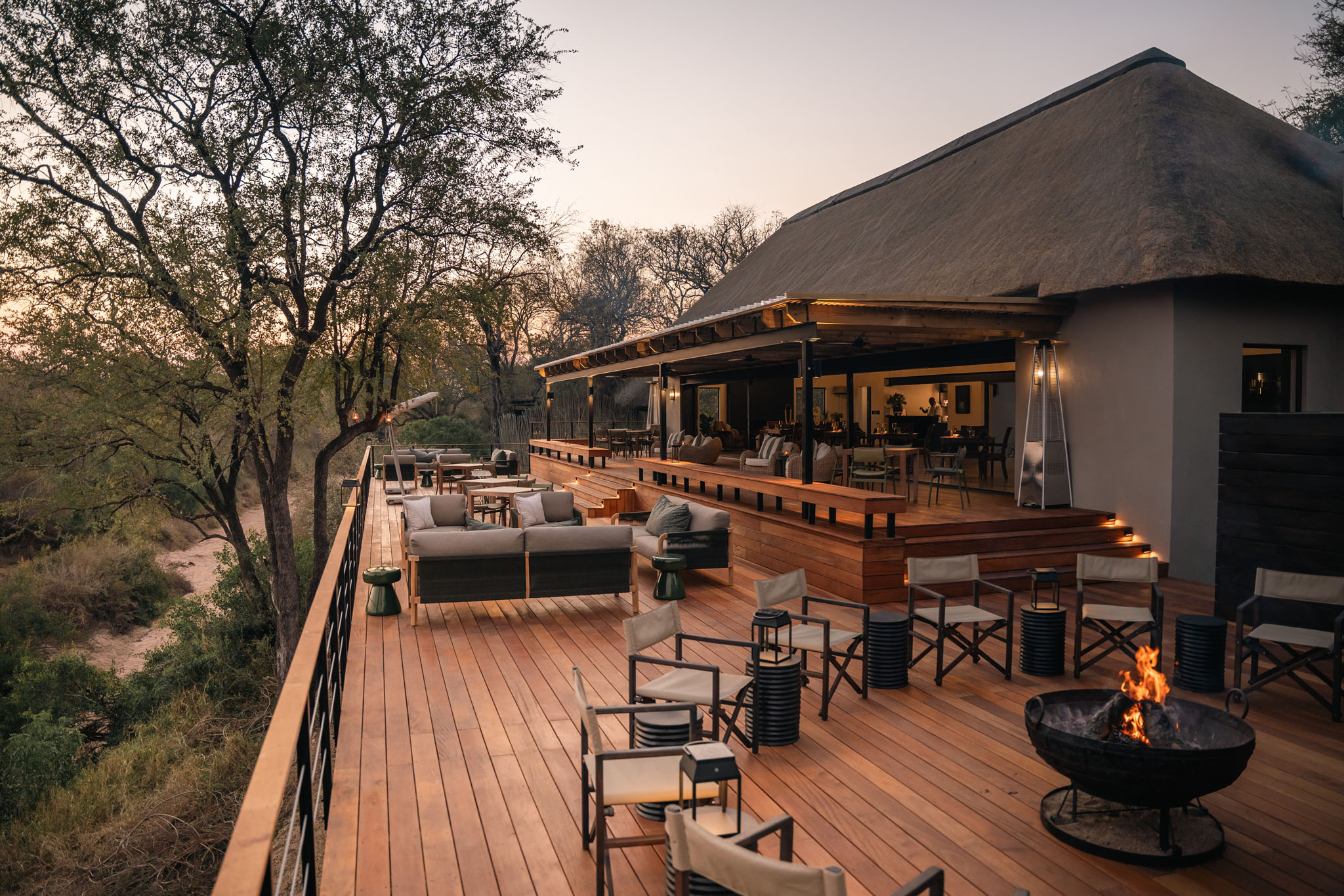 fireplace and dining area on deck of thornybush simbambili lodge at sunset