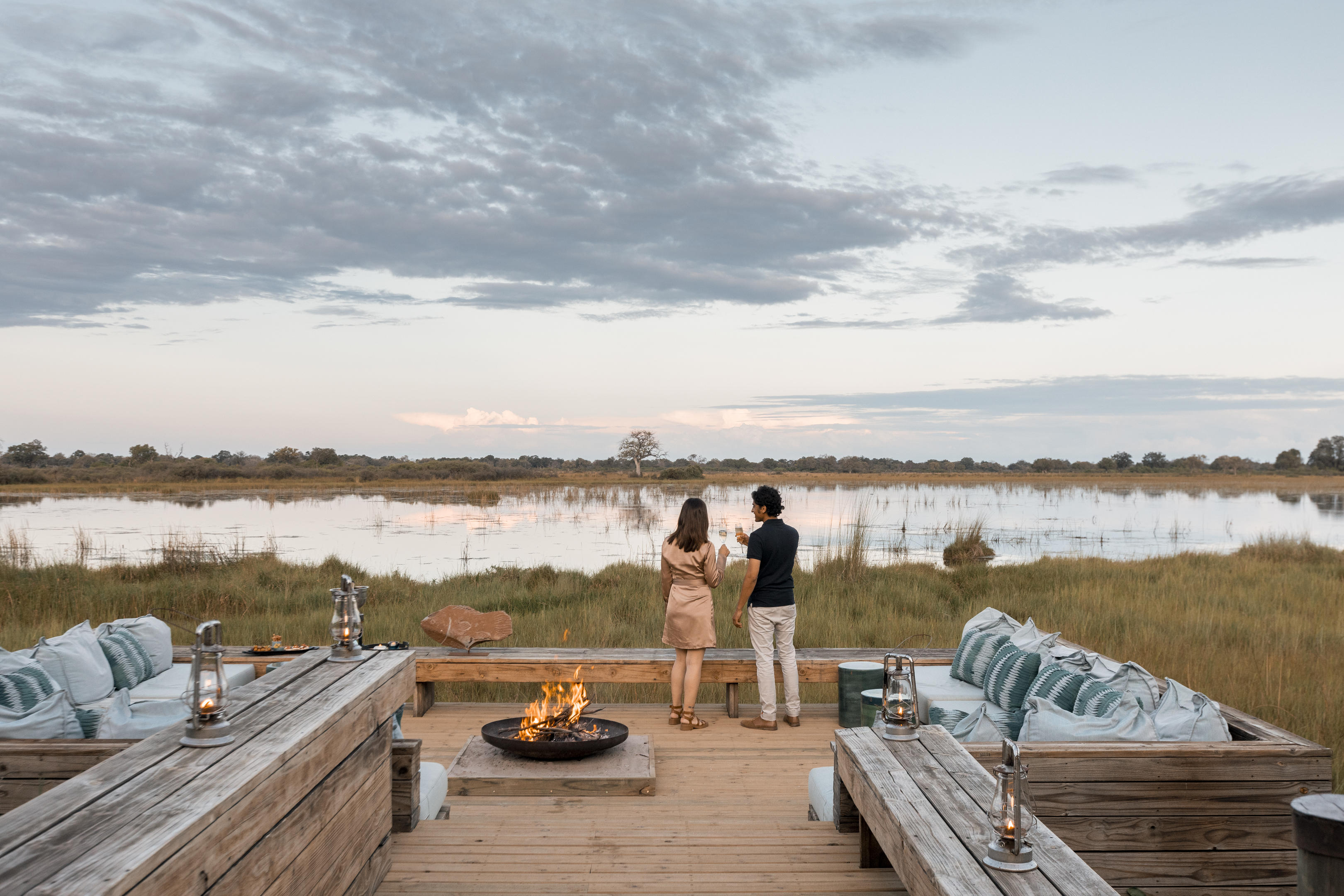 guests by fireplace on deck looking out to delta at Vumbura Plains Camp Wilderness Botswana Okavango Delta